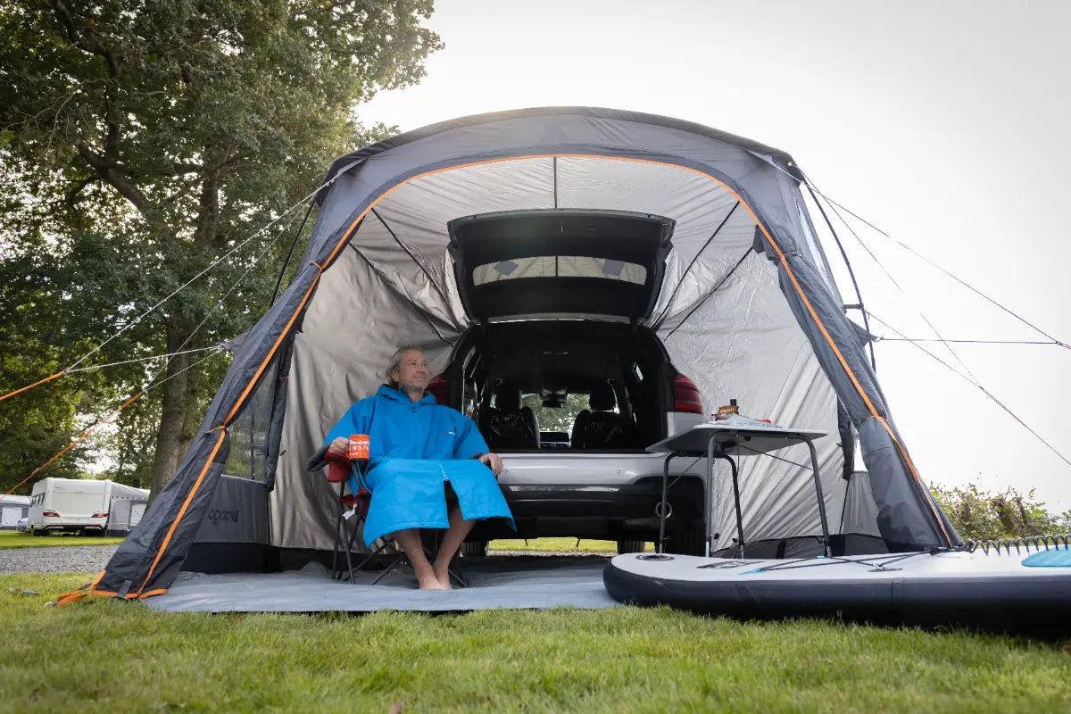 Person sitting inside the Vango Arden Tailgate Low Poled Awning attached to a car with outdoor gear around