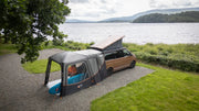 Van with a Vango Tailgate Airhub II Low awning parked by a lake.